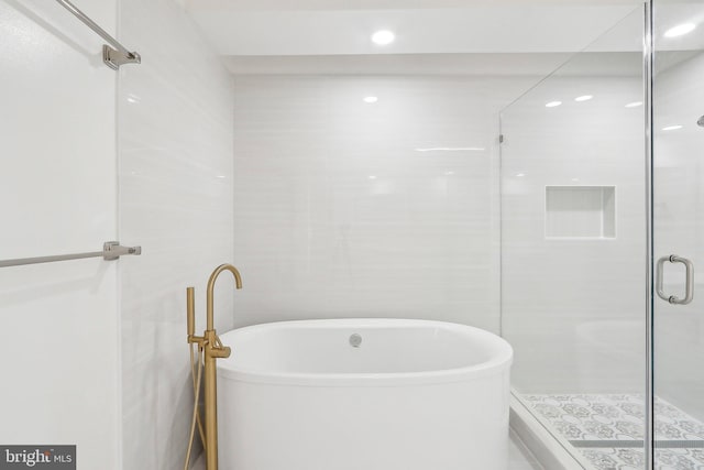 bathroom featuring plus walk in shower and tile walls