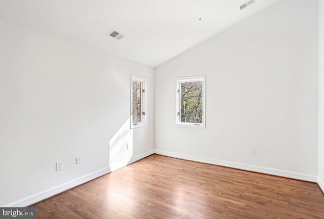 unfurnished room with hardwood / wood-style floors and vaulted ceiling