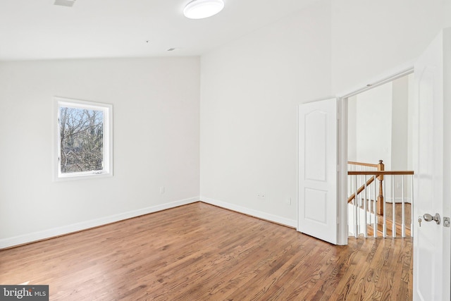 spare room featuring wood-type flooring and lofted ceiling