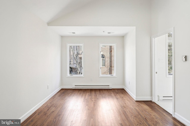 spare room featuring lofted ceiling, dark hardwood / wood-style floors, and a baseboard heating unit