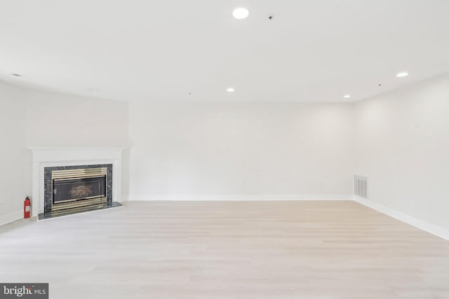 unfurnished living room with light hardwood / wood-style flooring and a high end fireplace