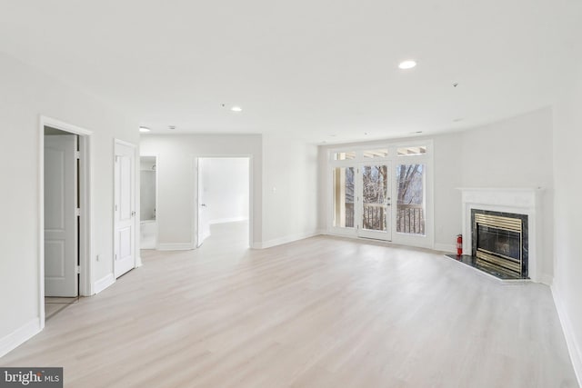 unfurnished living room featuring a premium fireplace and light wood-type flooring