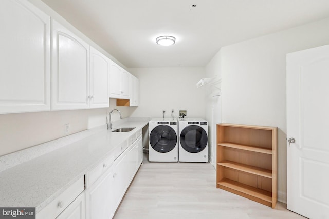 laundry area featuring cabinets, sink, light hardwood / wood-style floors, and washing machine and dryer