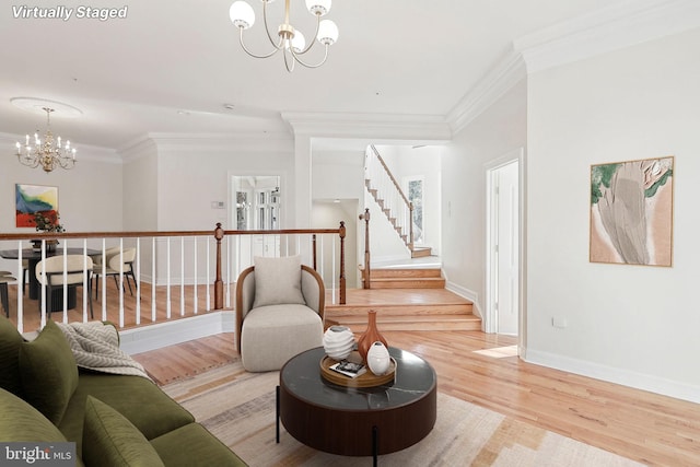 living room featuring an inviting chandelier, ornamental molding, and light hardwood / wood-style flooring