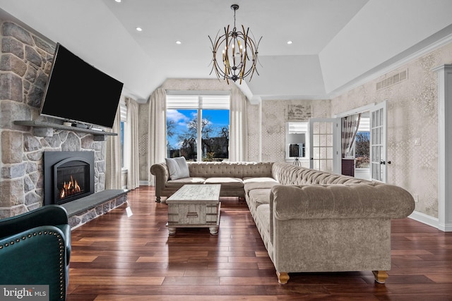 living room featuring a fireplace, dark wood-type flooring, vaulted ceiling, and a notable chandelier