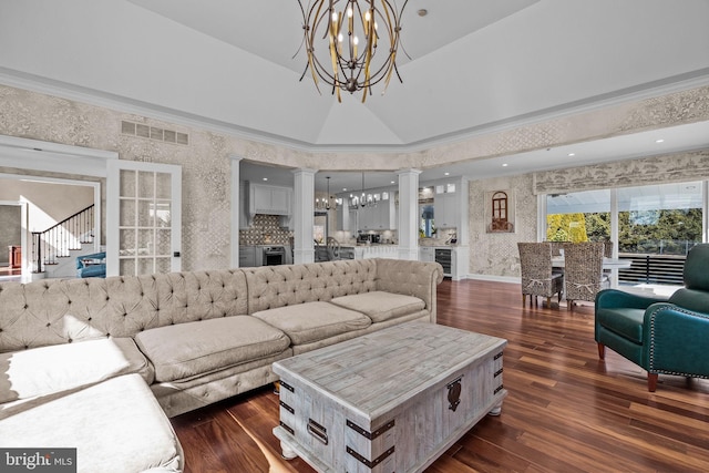 living room featuring wine cooler, ornate columns, dark hardwood / wood-style floors, and an inviting chandelier