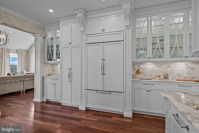 kitchen with white cabinets, ornate columns, light stone counters, and ornamental molding