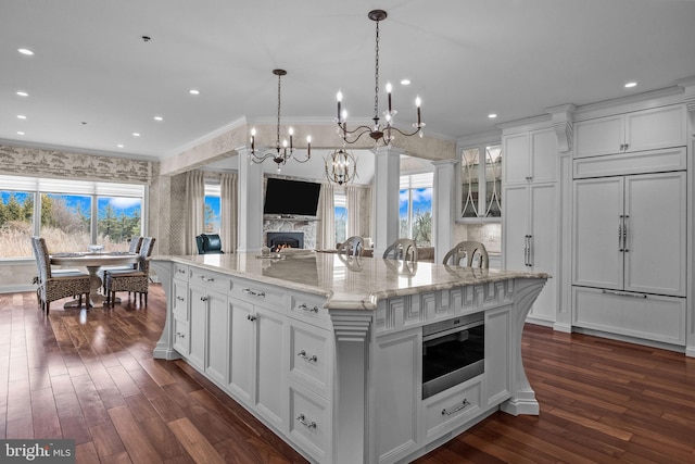 kitchen featuring a spacious island, dark wood-type flooring, white cabinets, stainless steel microwave, and pendant lighting