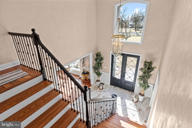 entrance foyer featuring french doors, a towering ceiling, and hardwood / wood-style floors