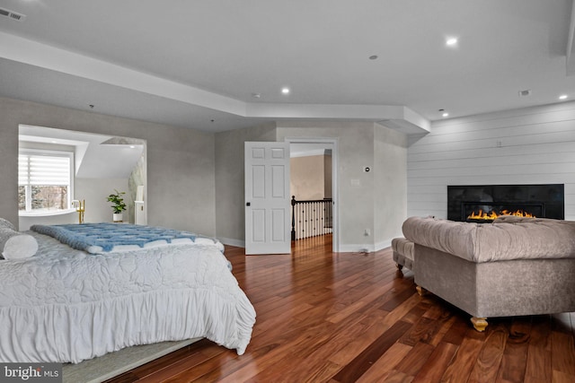 bedroom featuring dark wood-type flooring and a large fireplace