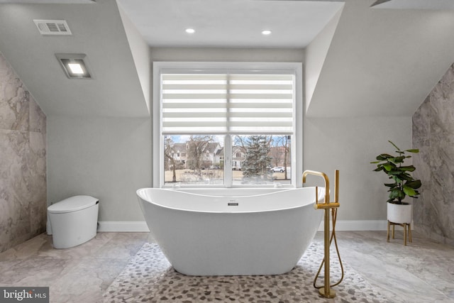 bathroom featuring vaulted ceiling and a tub to relax in