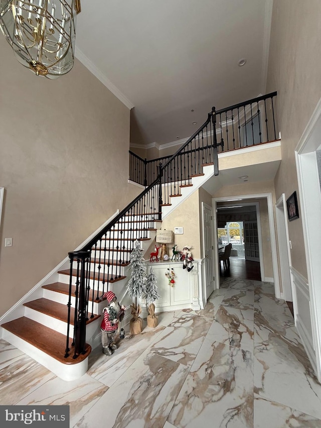 foyer featuring a high ceiling, crown molding, and a notable chandelier