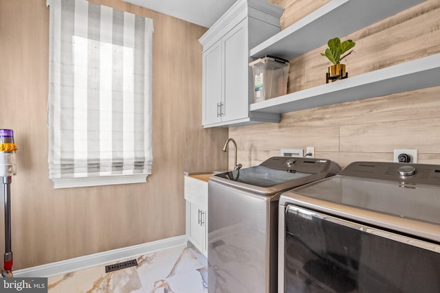 clothes washing area with separate washer and dryer and cabinets