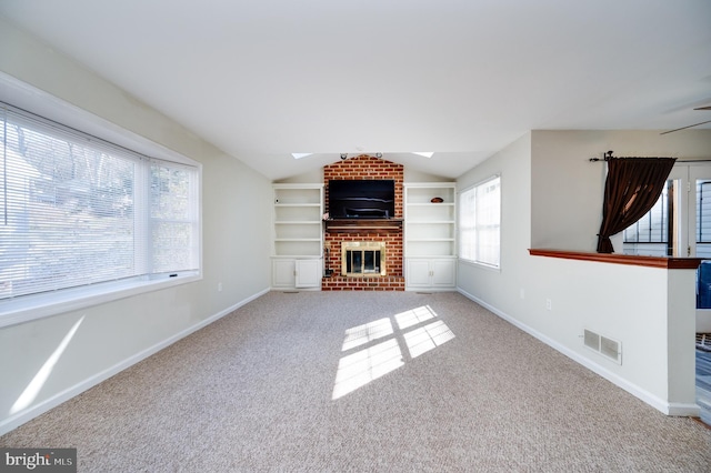 unfurnished living room with light carpet, a fireplace, vaulted ceiling with skylight, and built in features