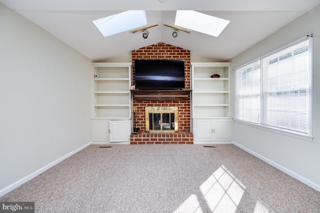 unfurnished living room featuring built in features, a brick fireplace, lofted ceiling, and carpet