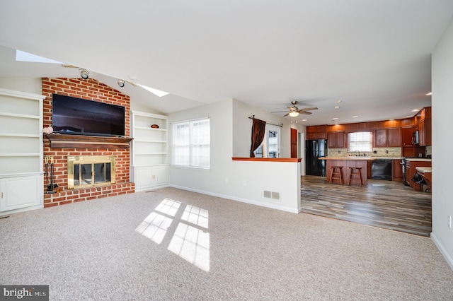 unfurnished living room with lofted ceiling, a brick fireplace, carpet, and built in shelves