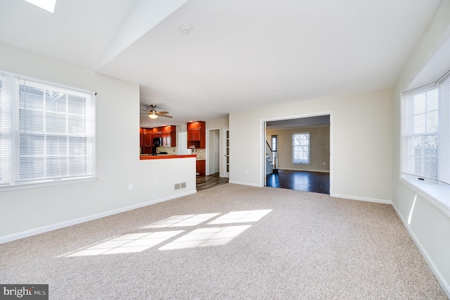 unfurnished living room featuring lofted ceiling, a wealth of natural light, and carpet flooring