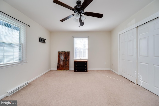 unfurnished bedroom with ceiling fan, light colored carpet, baseboard heating, and a closet