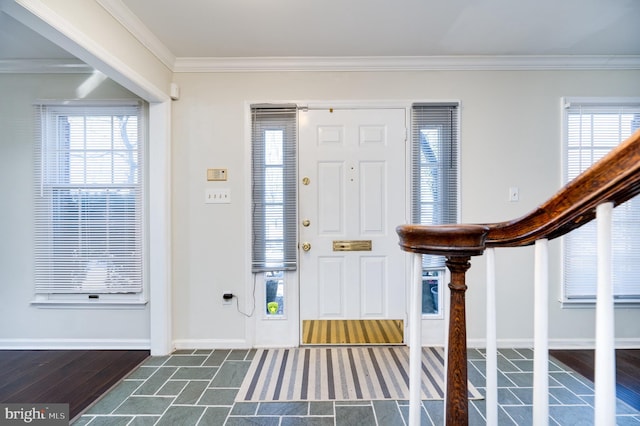 entryway with dark wood-type flooring, ornamental molding, and a wealth of natural light