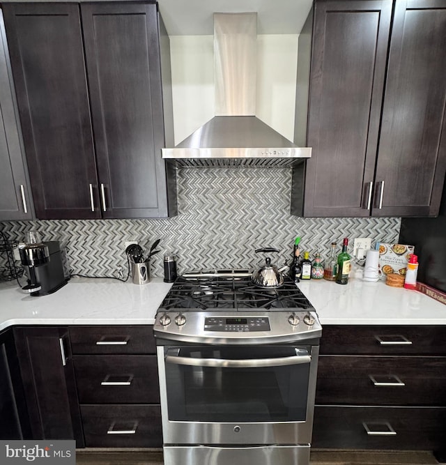 kitchen featuring dark brown cabinets, gas stove, decorative backsplash, and wall chimney range hood