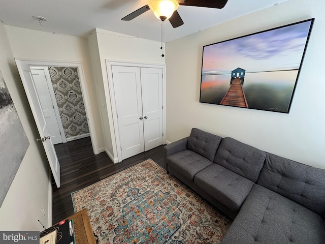 living room featuring dark wood-type flooring and ceiling fan