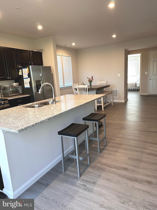 kitchen featuring light stone countertops, stainless steel fridge, a kitchen breakfast bar, and light hardwood / wood-style floors