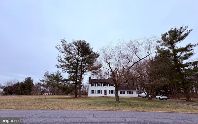 view of front facade with a chimney and a front lawn
