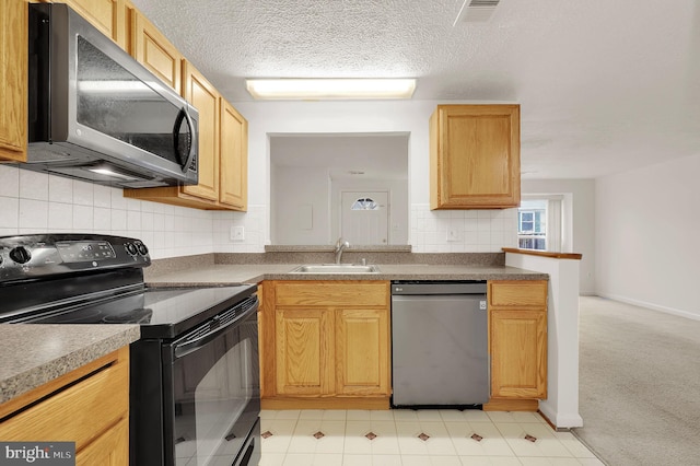 kitchen with sink, light carpet, a textured ceiling, stainless steel appliances, and decorative backsplash