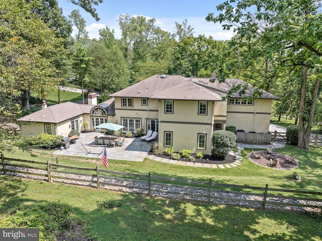 rear view of property featuring a yard, a patio area, and french doors