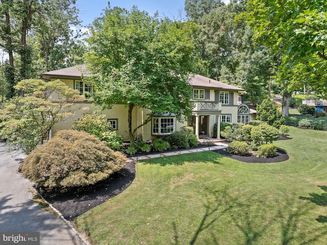 view of front of house featuring a balcony and a front lawn