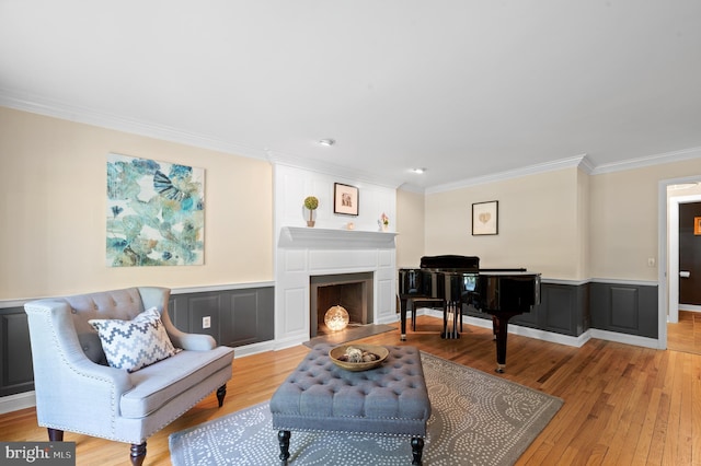 living area featuring crown molding, a fireplace, and light hardwood / wood-style floors