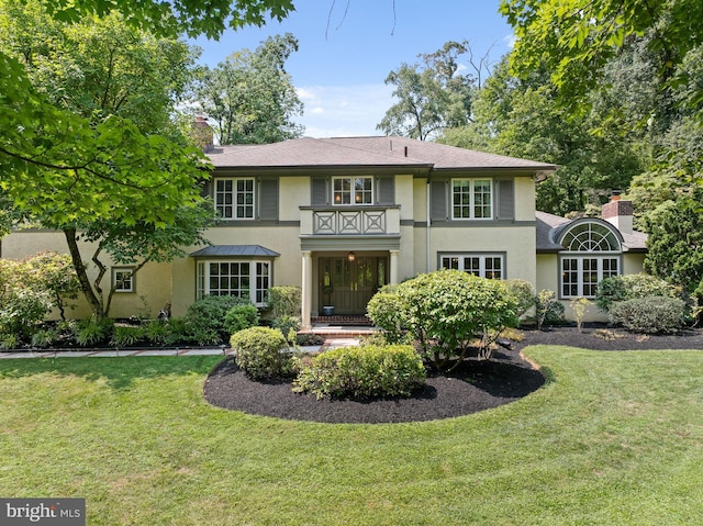 rear view of property with a balcony and a lawn