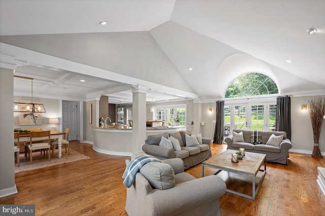 living room with hardwood / wood-style flooring, high vaulted ceiling, and ornate columns