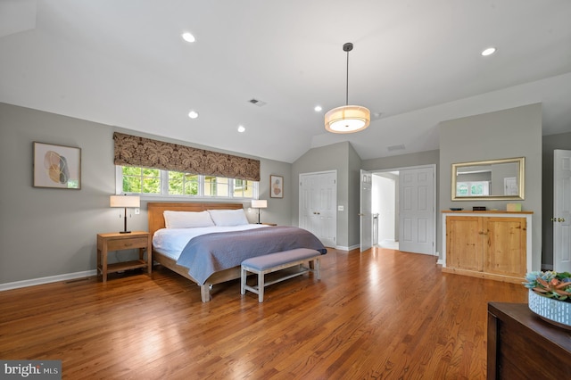 bedroom with hardwood / wood-style flooring, vaulted ceiling, and a closet