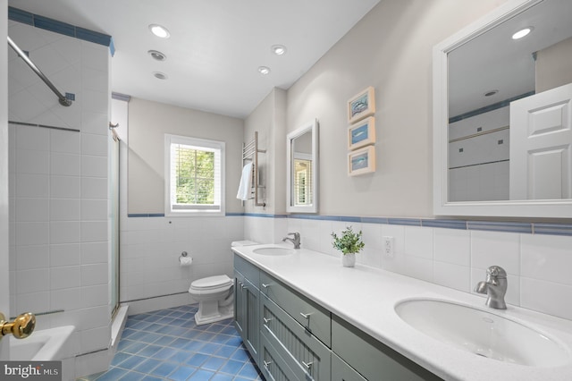 bathroom featuring tiled shower, toilet, tile walls, vanity, and tile patterned flooring