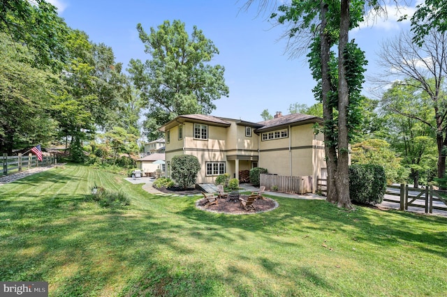 rear view of property with an outdoor fire pit and a yard