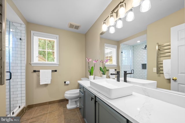 bathroom featuring tile patterned flooring, vanity, a shower with shower door, and toilet