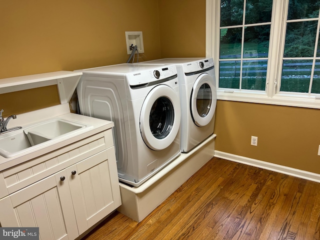 laundry room with cabinets, wood-type flooring, sink, and washer and dryer