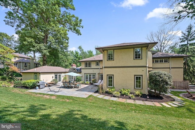 rear view of house featuring a lawn, french doors, and a patio area