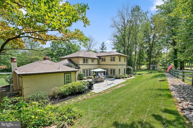 back of property with a yard, a storage unit, and a patio area