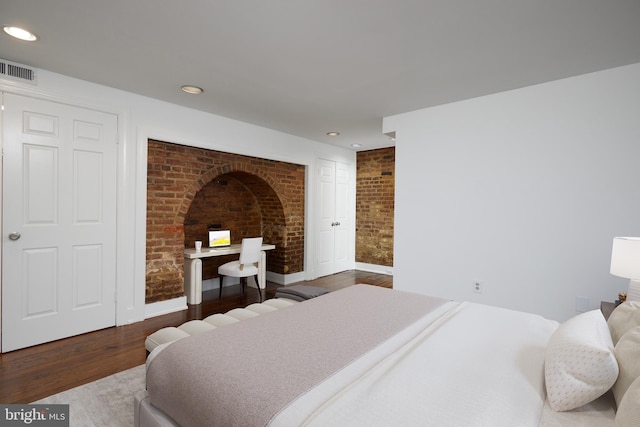 bedroom featuring hardwood / wood-style flooring and brick wall