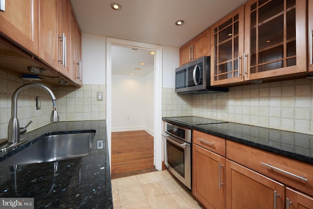 kitchen with sink, appliances with stainless steel finishes, tasteful backsplash, light tile patterned flooring, and dark stone counters