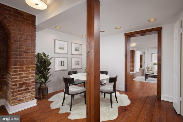 dining room featuring dark hardwood / wood-style floors and brick wall