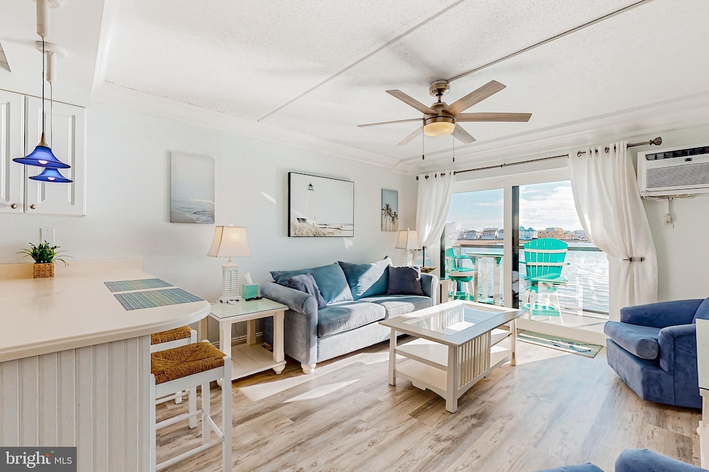 living room featuring ornamental molding, a wall unit AC, light hardwood / wood-style floors, and ceiling fan