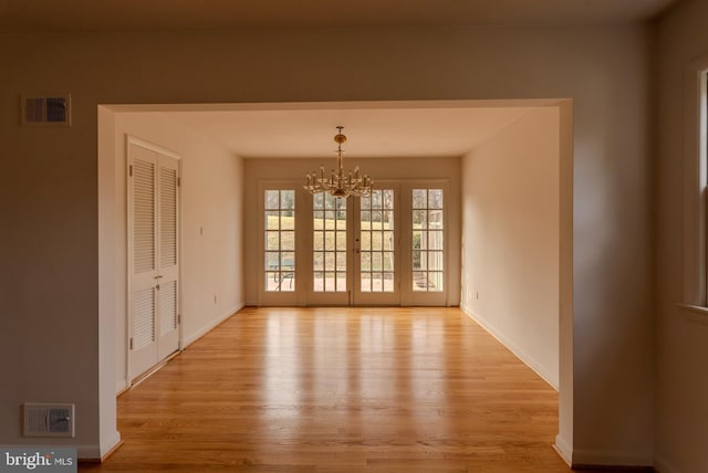 unfurnished dining area with an inviting chandelier and light hardwood / wood-style floors