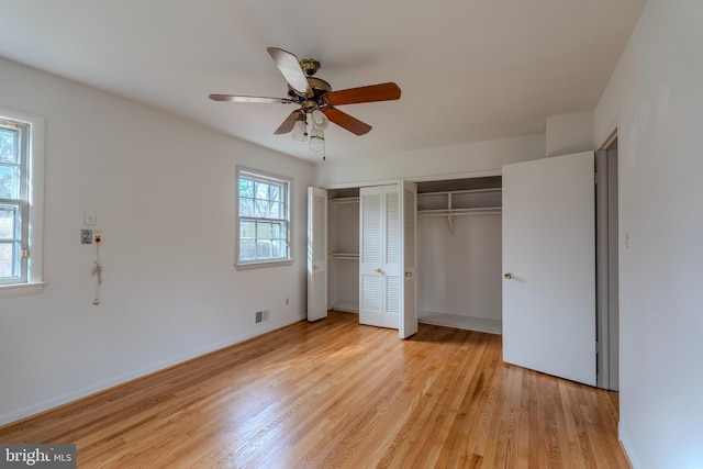 unfurnished bedroom with two closets, light hardwood / wood-style flooring, and ceiling fan