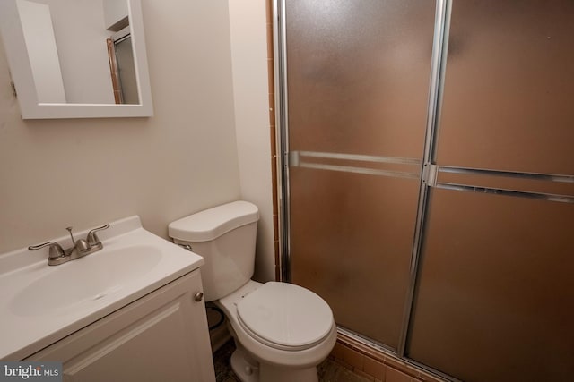 bathroom featuring vanity, a shower with shower door, and toilet