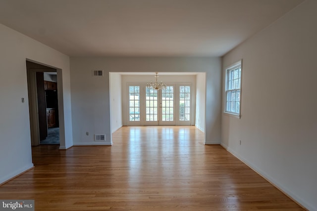 empty room with an inviting chandelier and light wood-type flooring