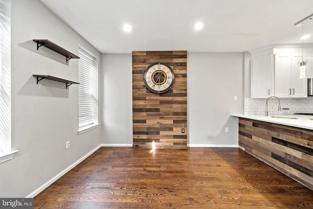 unfurnished living room with a sink, baseboards, recessed lighting, and dark wood-style flooring