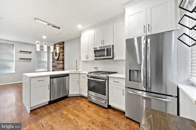 kitchen featuring dark wood-style floors, a peninsula, light countertops, appliances with stainless steel finishes, and white cabinetry